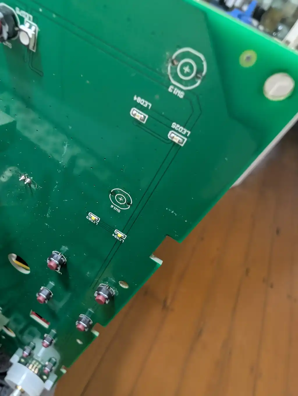 The same DJ controller pad board with two switch positions stripped bare, ready for the replacement tactile switches.