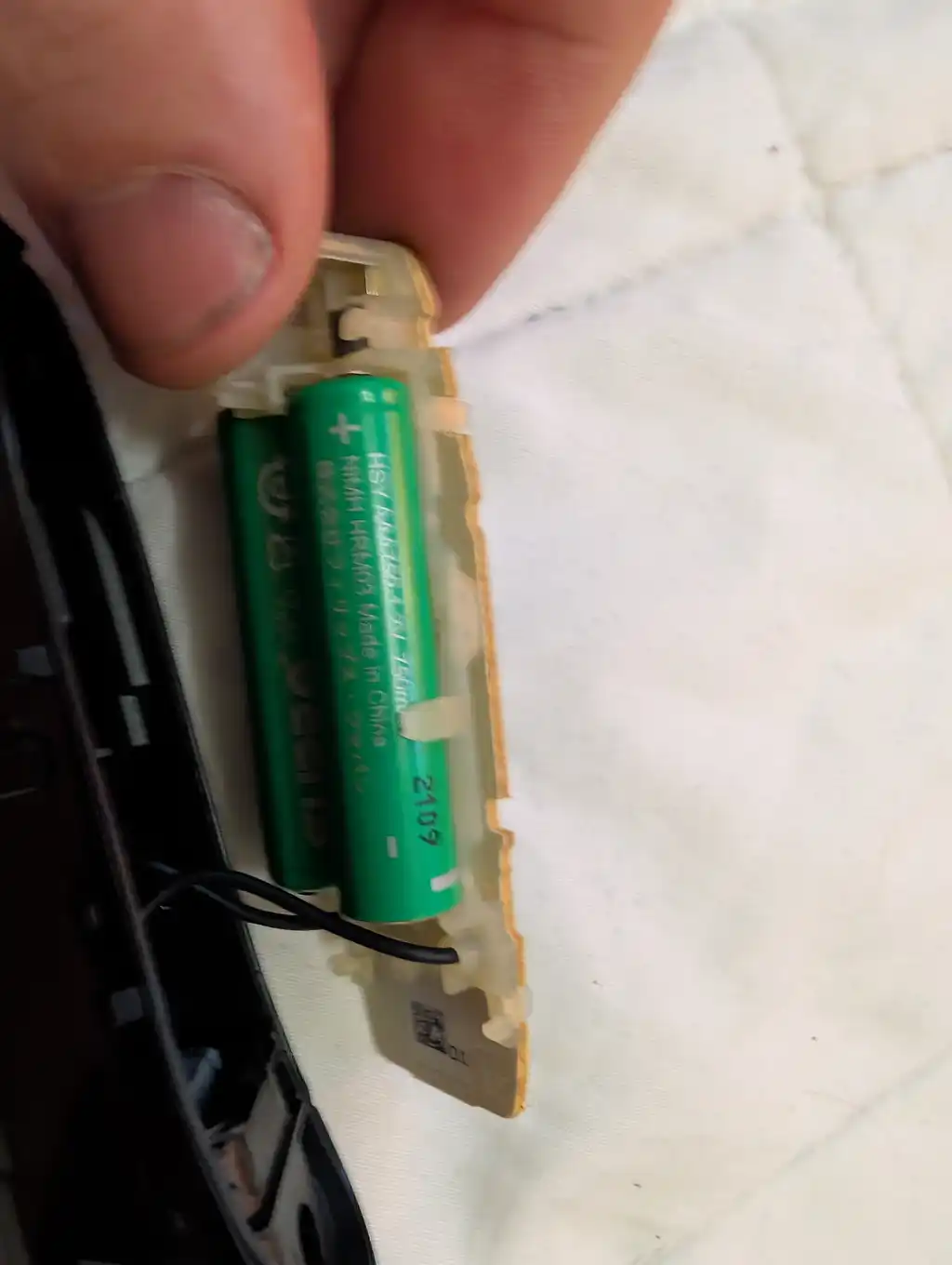 Close-up of the Philips electric shaver's battery carrier held in hand, showing both NiMH cells and their solder tags.