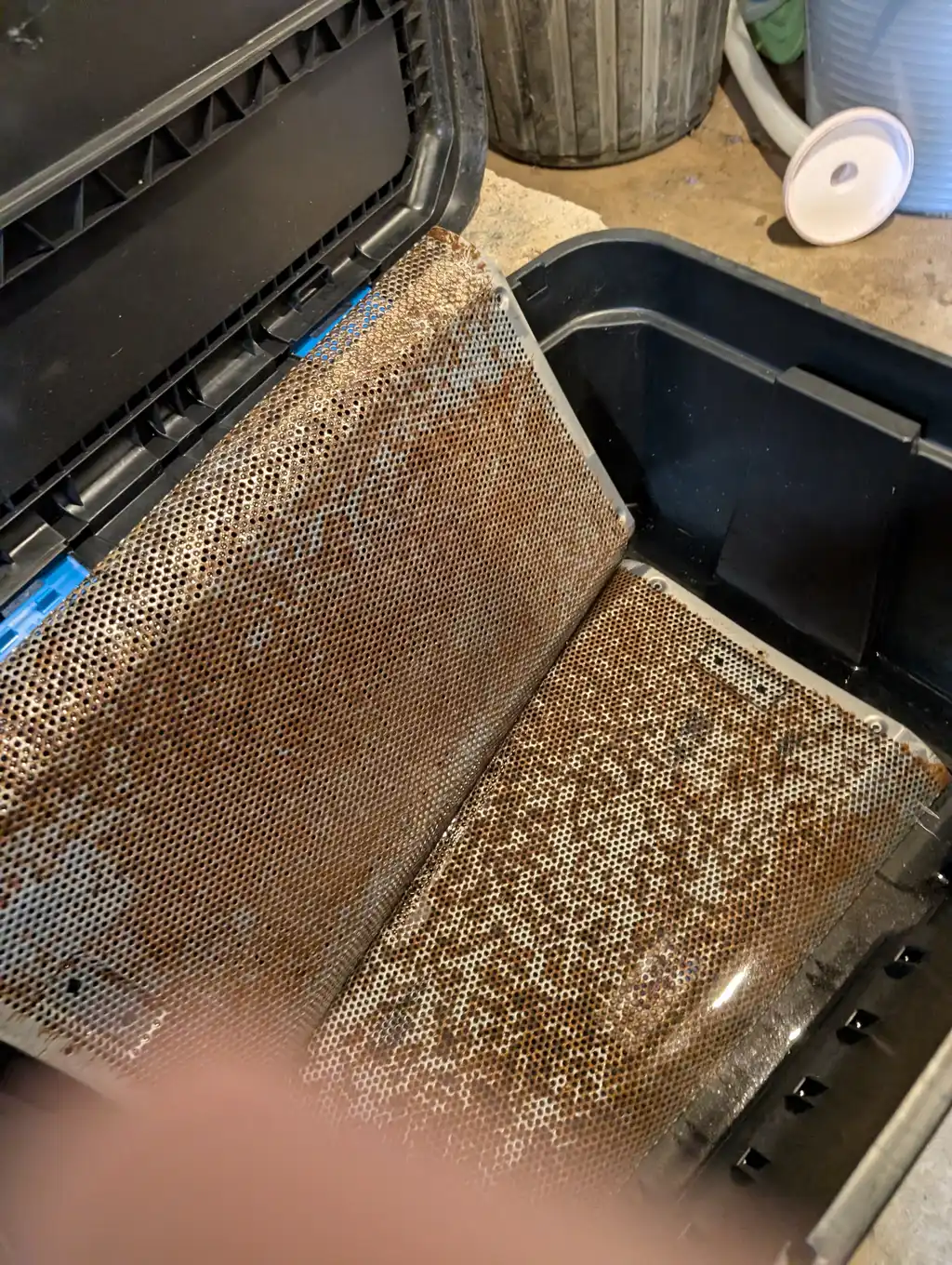 Both of the QSC speaker's steel grilles soaking in vinegar, the rust lifting off after the old paint was stripped.