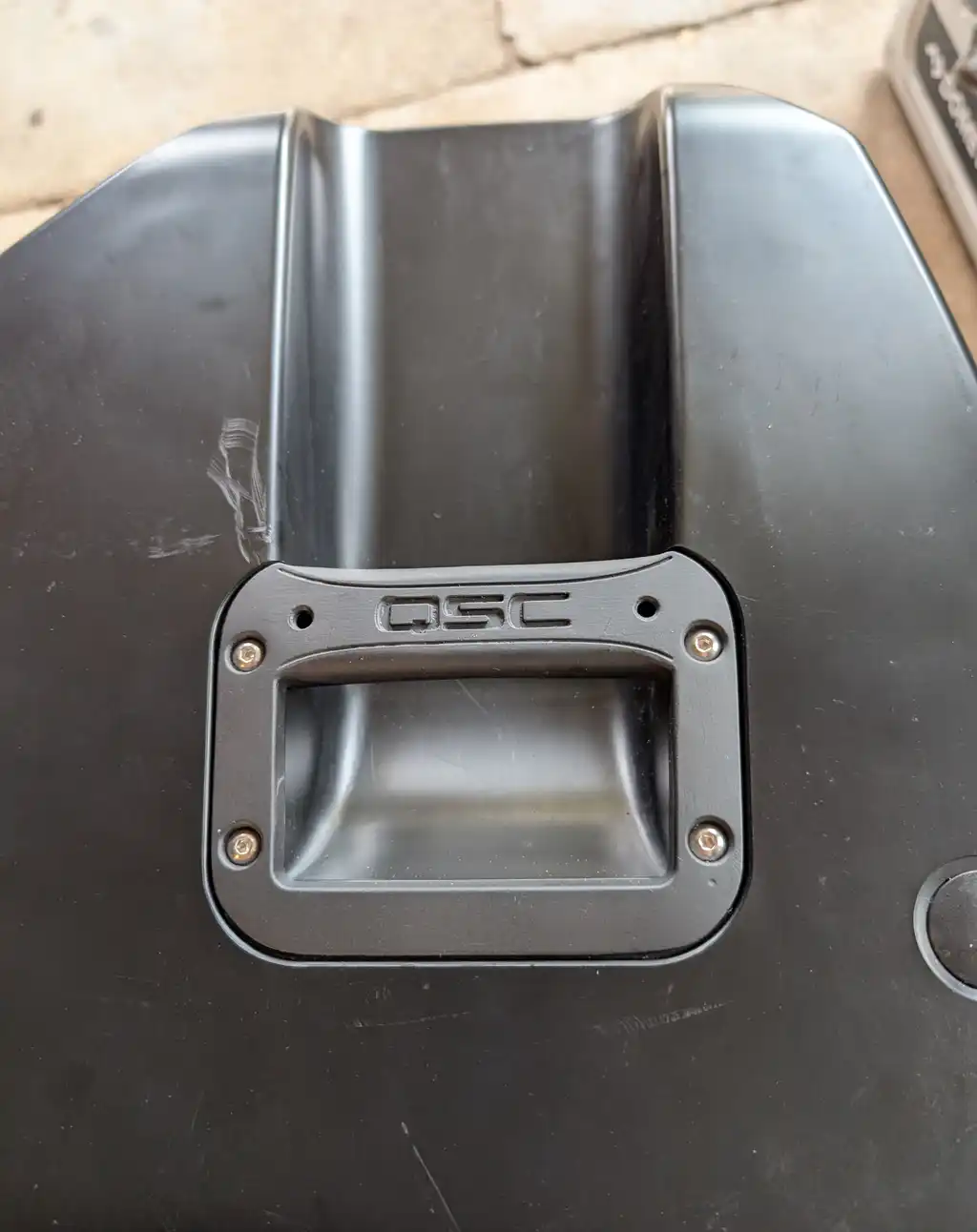 One of the QSC speaker's own repainted handles fitted back into its cleaned recess on the cabinet, held by fresh screws.